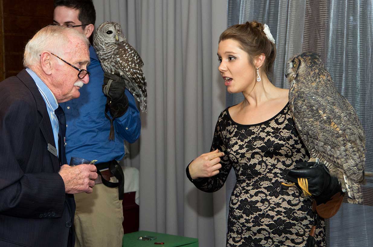 People holding 2 owls