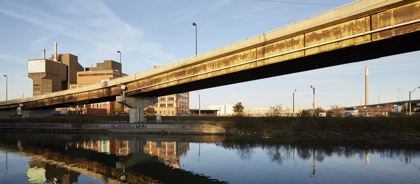 an industrial building and overpass are reflected in the still waters of the Don River