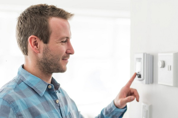 homeowner adjusts home heating and cooling settings on control panel