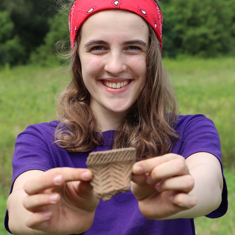 Boyd Archaeological Field School student displays artifact unearthed at dig site