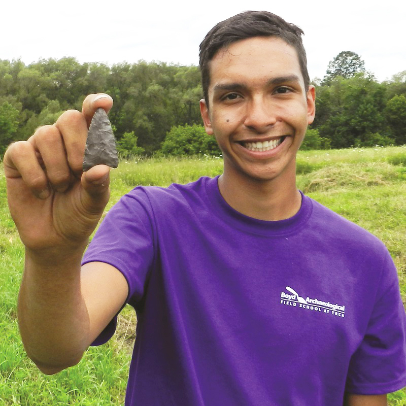 Boyd Archaeological Field School student displays artifact unearthed at dig site