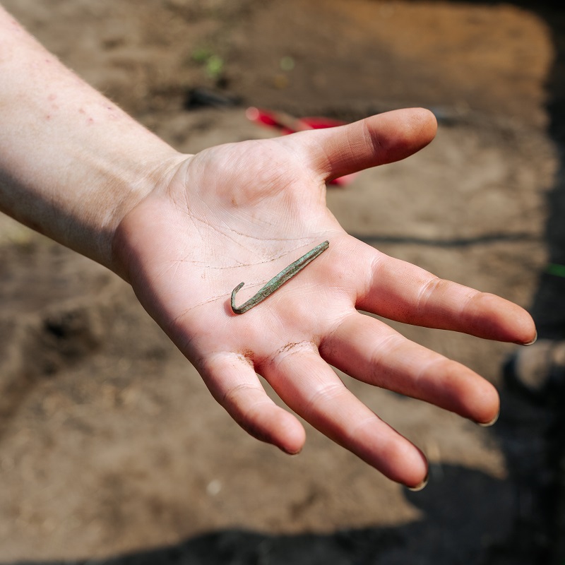 Boyd Archaeological Field School student displays artifact unearthed at dig site