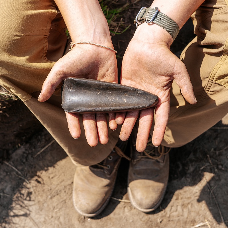 Boyd Archaeological Field School student displays artifact unearthed at dig site