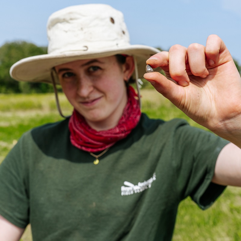 Boyd Archaeological Field School student displays artifact unearthed at dig site